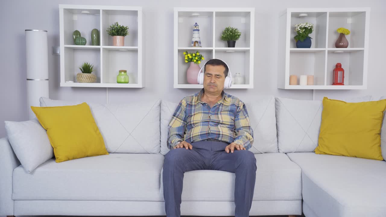 불행한 노인이 헤드폰으로 음악을 듣고 있습니다.