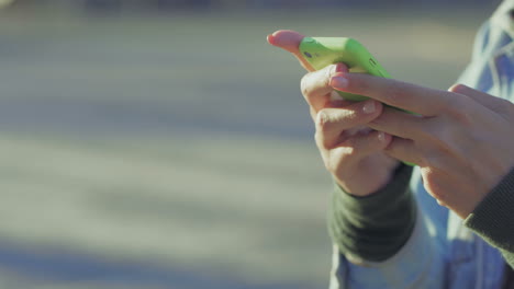 closeup view of female hands texting on green smartphone.