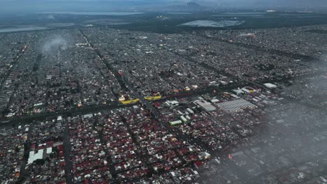 Drone flying through clouds, offering a glimpse of Ecatepec municipality in Mexico below