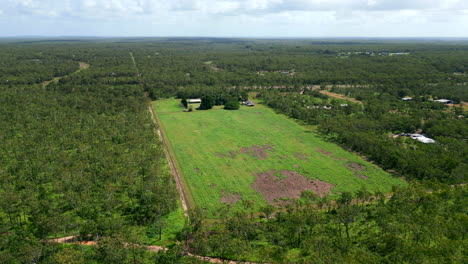 Drone-Aéreo-De-Una-Superficie-Rural-Del-Interior-De-Un-Bloque-Enorme-Con-Una-Casa-Situada-En-Un-Campo-Abierto-Despejado-Entre-Un-Denso-Bosque-Tropical