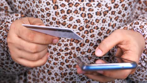 persona que utiliza un teléfono inteligente y una tarjeta de crédito para el pago móvil