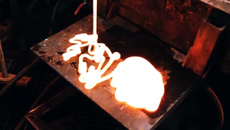 glassblower pouring molten glass on metal work bench