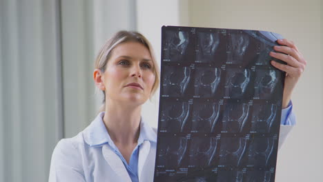 una mujer médica con una bata blanca de pie en el pasillo del hospital mirando una tomografía computarizada o una resonancia magnética