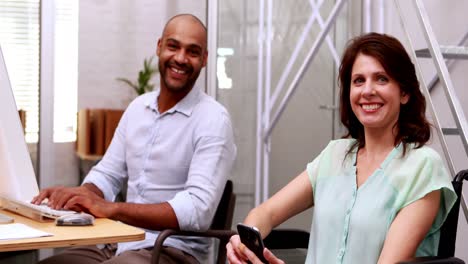 casual businesswoman in wheelchair talking with colleague