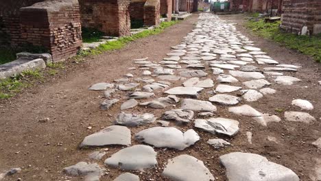 camino romano pavimentado con piedra separando insulae en el enorme y mundialmente famoso sitio arqueológico de ostia antica en las afueras de roma