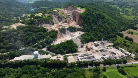 trucks and machinery parked near structures and buildings on a hill where raw materials are extracted for cement