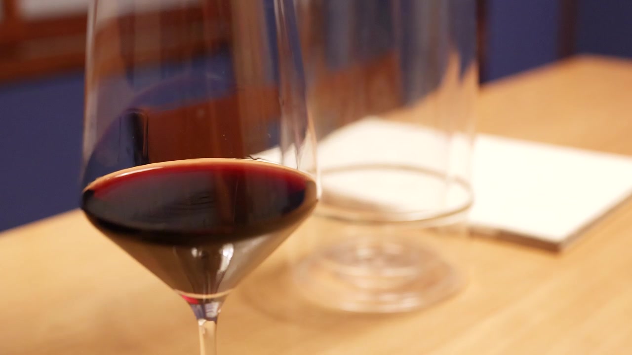 Primo piano di un bicchiere di vino rosso con bottiglia rimossa dal refrigeratore.