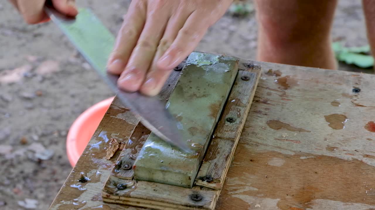 A large fish filleting knife being sharpened on a wet sharpening stone to prepare freshly caught sea fish for lunch and dinner