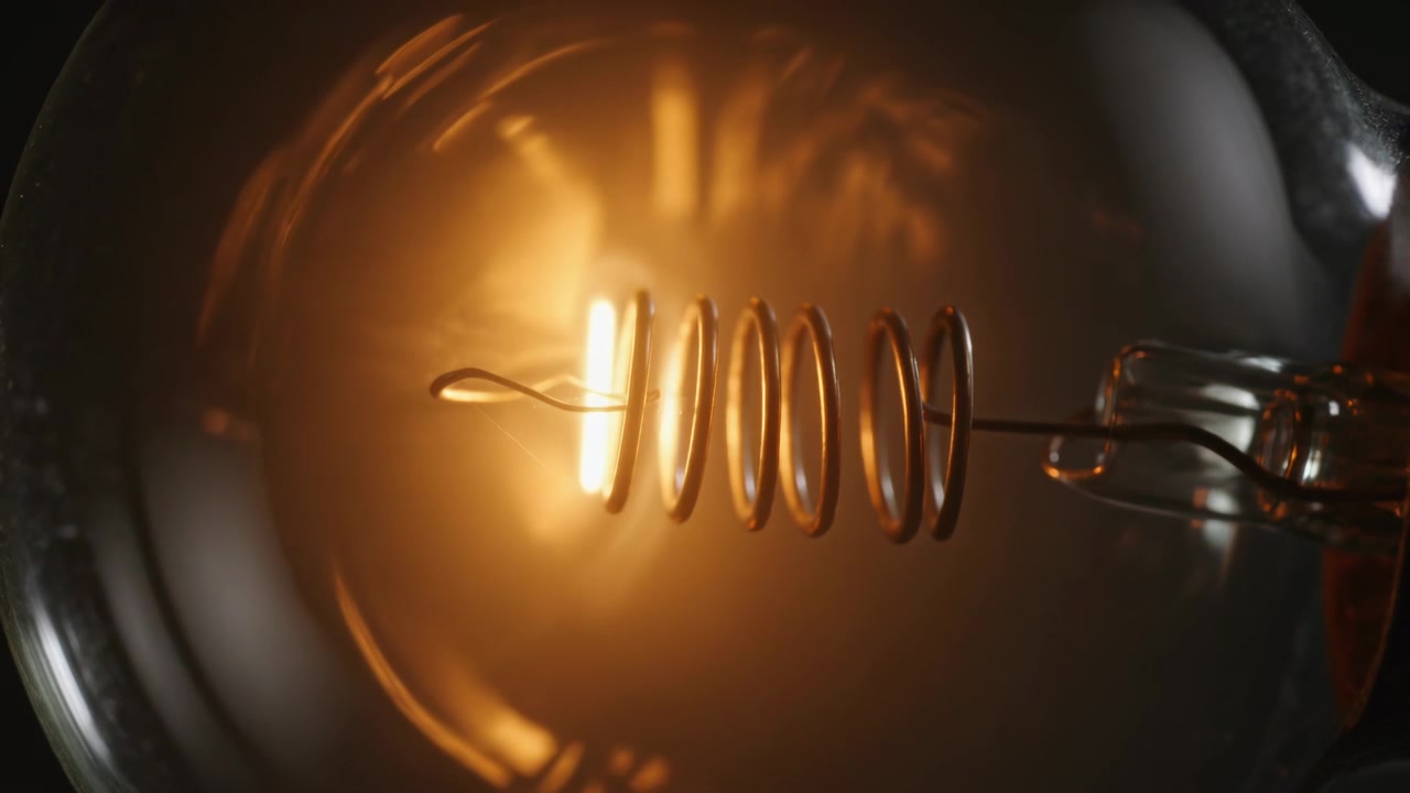 Filamento a spirale tremolante che si affievolisce e poi si spegne dopo un'interruzione di corrente in studio, con un bagliore di vetro.