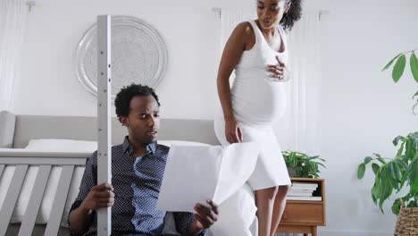 african american couple with pregnant woman look at instructions for building self assembly baby cot