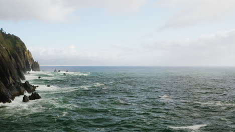 Aerial-view-flying-over-Pacific-Ocean-towards-distant-horizon,-along-Oregon-Coast