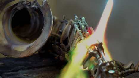 A-blacksmith-uses-gas-welding-to-melt-a-brass-saxophone,-resulting-in-destructive-sparks-and-brightly-coloured-flames