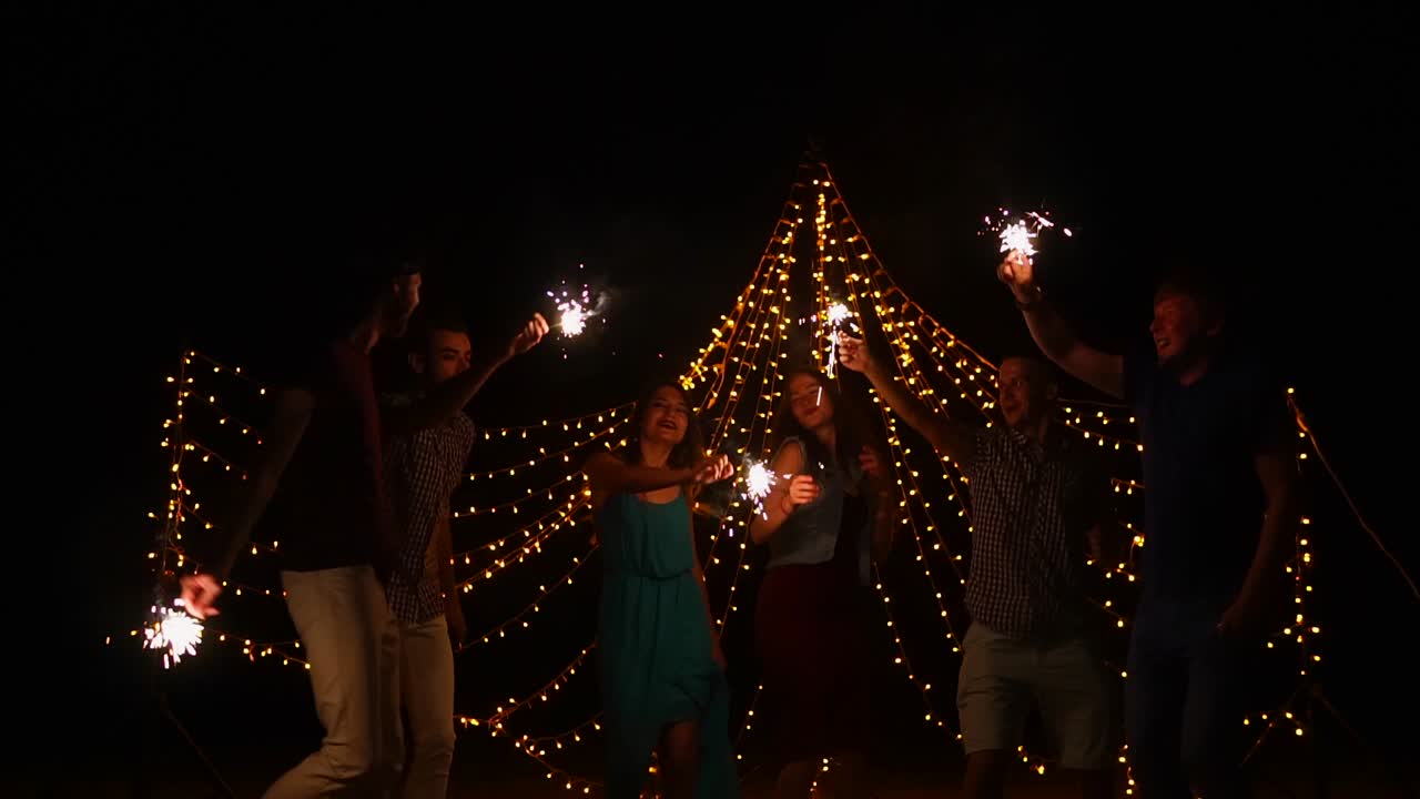 Amici che festeggiano con stelline luminose di notte