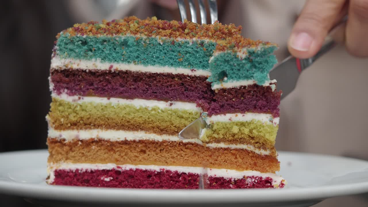 Close-up of a Slice of Colorful Rainbow Cake Being Cut