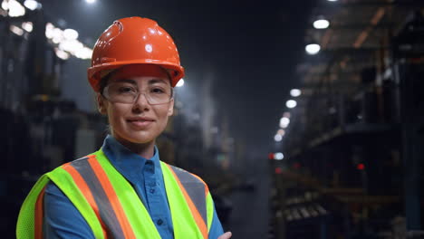 mujer ingeniera sonriendo cámara con casco de seguridad en el almacenamiento industrial enorme.