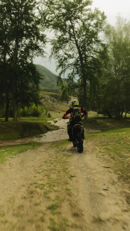 motorcyclist rides across creek at racing fpv. courageous biker on motorcycle walkthrough offroad route in virgin nature. mud drops on camera
