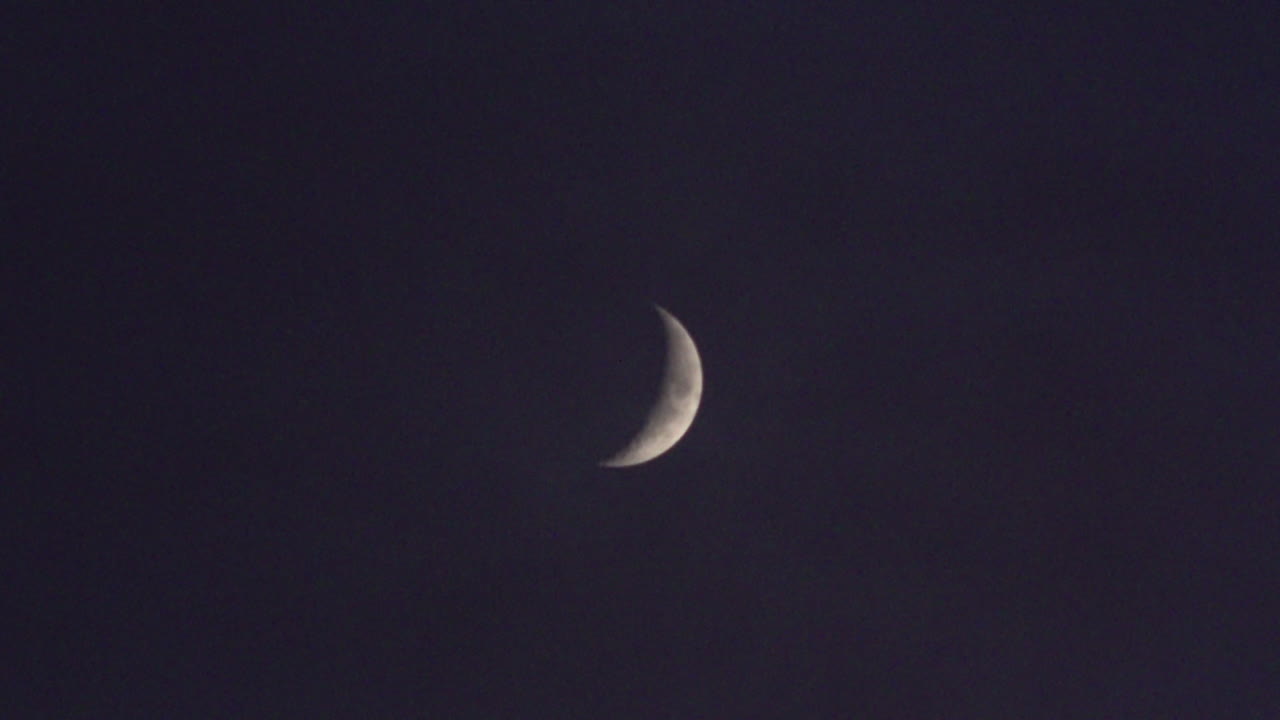 A passenger plane passes just underneath a waxing crescent moon at night.