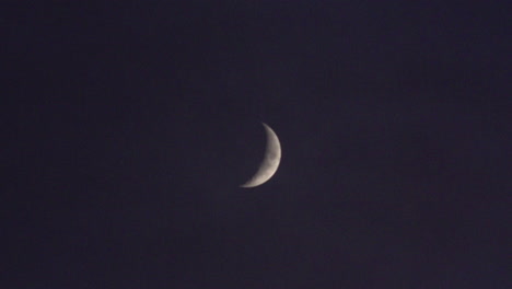 a passenger plane passes just underneath a waxing crescent moon at night.