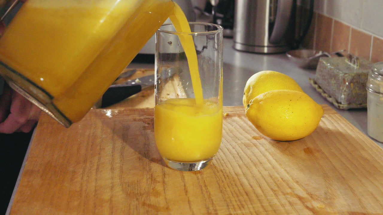 Versando succo d'ananas appena fatto in un bicchiere