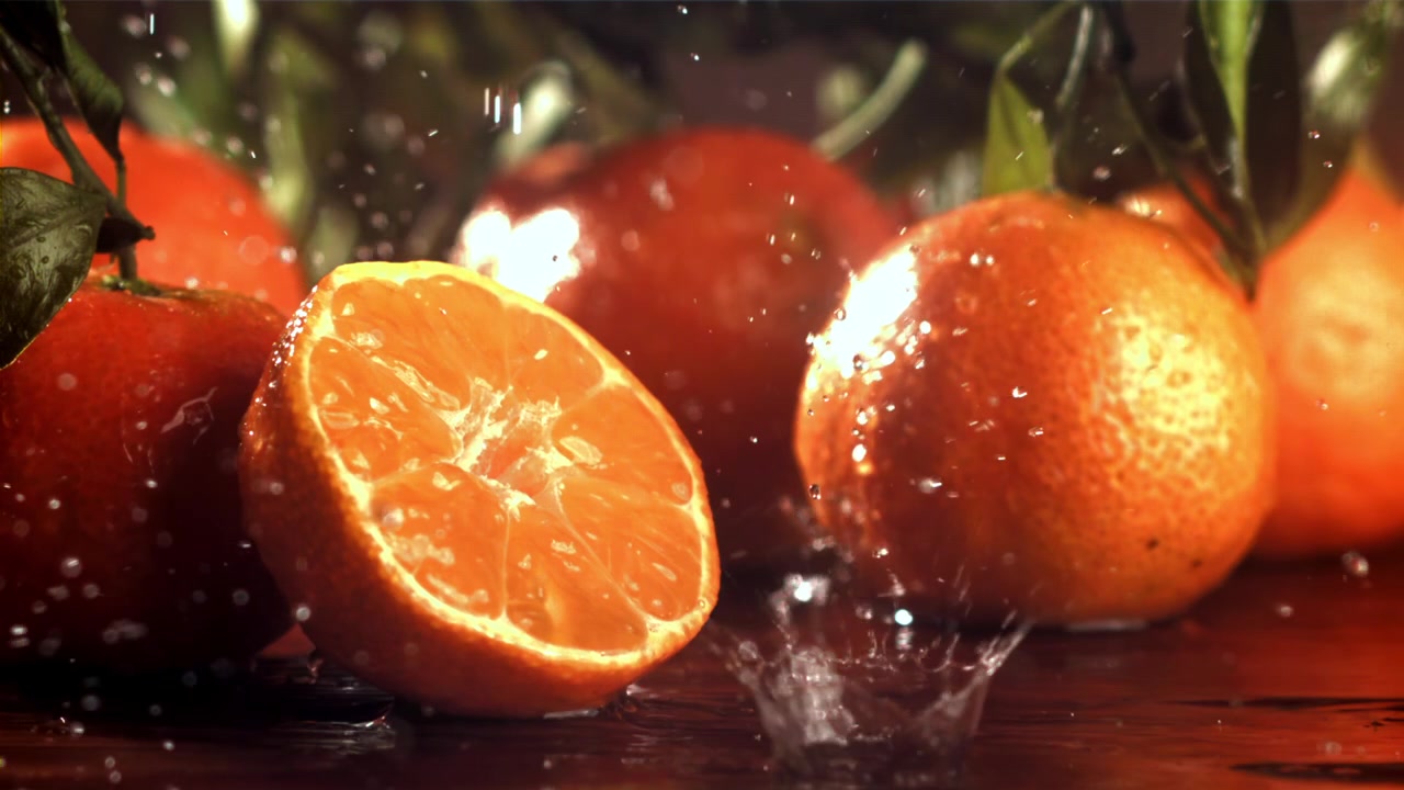 Schizzi d'acqua al rallentatore su mandarini e clementine freschi
