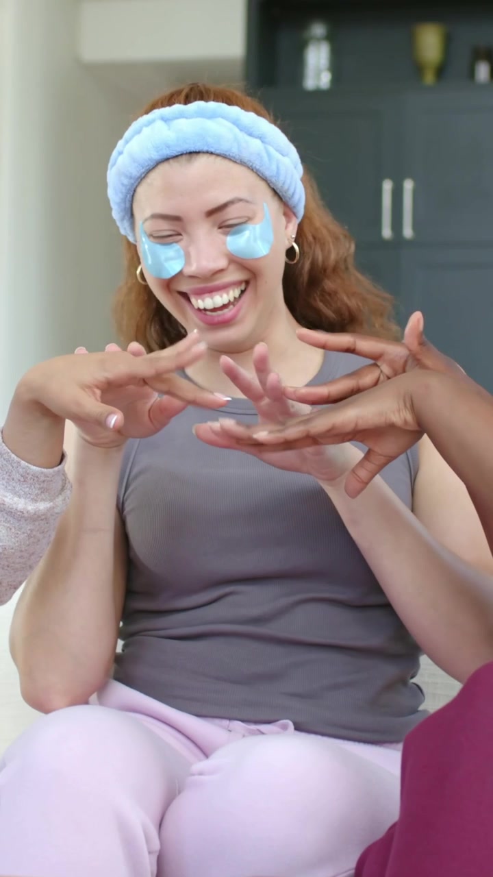 Video verticale: Donna che ride, sistema cerotti blu e una fascia per capelli sul divano mentre una mano la stuzzica.