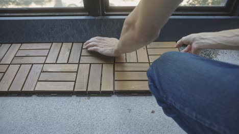 Cropped-Person-Landscaping-Patio-With-Interlocking-Wooden-Deck-Tiles