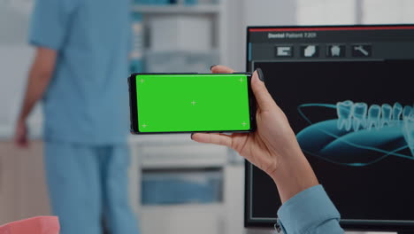 Close-up-of-orthodontist-holding-horizontal-green-screen