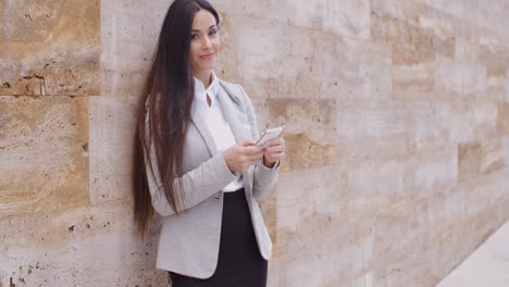 Business-woman-leaning-against-wall-texting