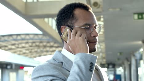 businessman with cell phone at train station