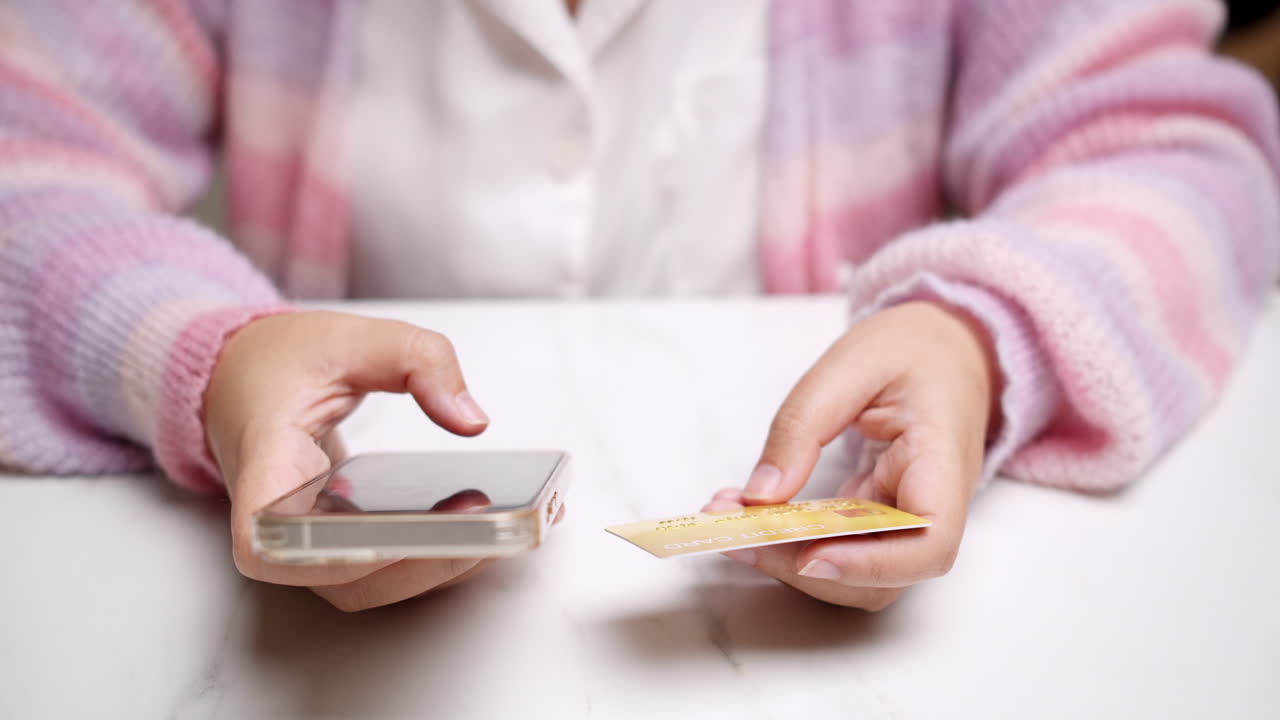 Close-up woman's hand holds a smartphone and use a mockup Bank credit card for online shopping services to pay money with cashless technology