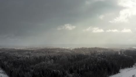 aerial view of dramatic sky over the forest with sun rays breaking through the clouds over a forest in winter landscape.