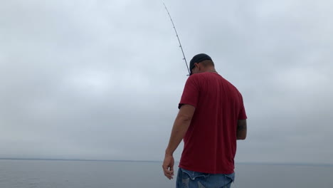 Man-fishing-off-of-boat-on-lake-in-summer