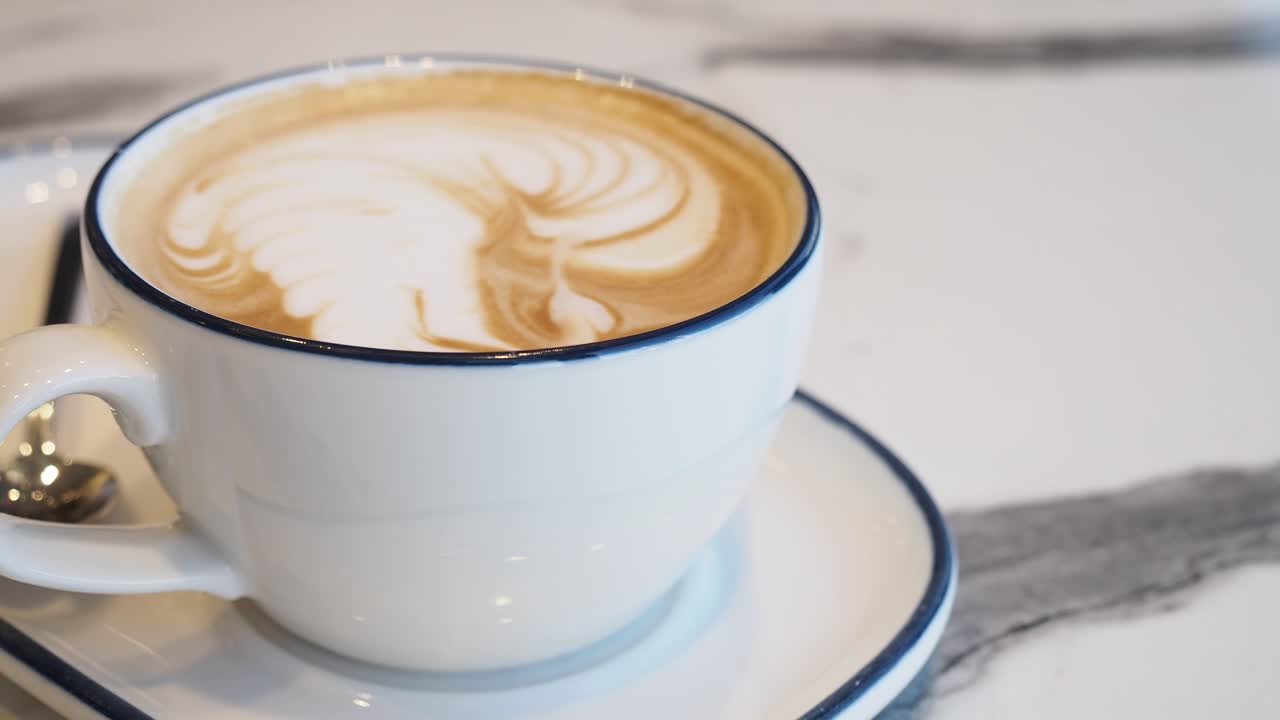 Primo piano di latte art in una tazza bianca su un tavolo di marmo