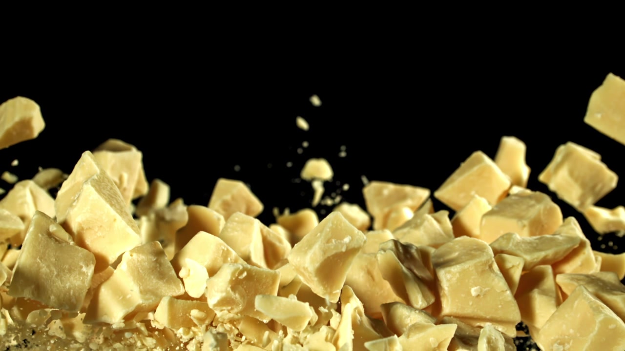 Pezzi di cioccolato bianco che cadono e si disperdono su sfondo nero