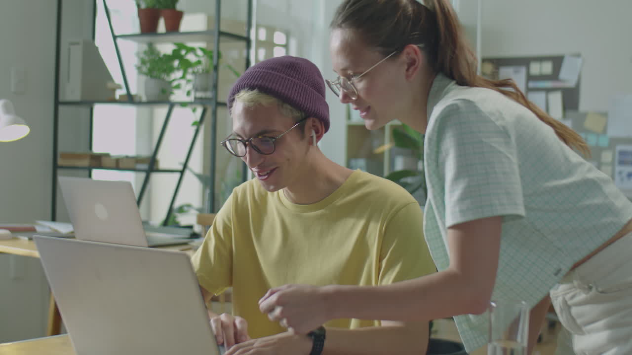 Cheerful Gen Z Colleagues Discussing Project on Laptop in Office