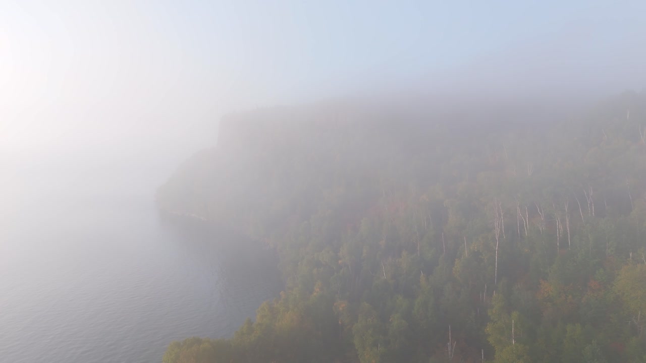 A thick morning fog blankets Lake Superior’s cliffs and forests, as early autumn colors emerge along Ontario’s rugged shoreline