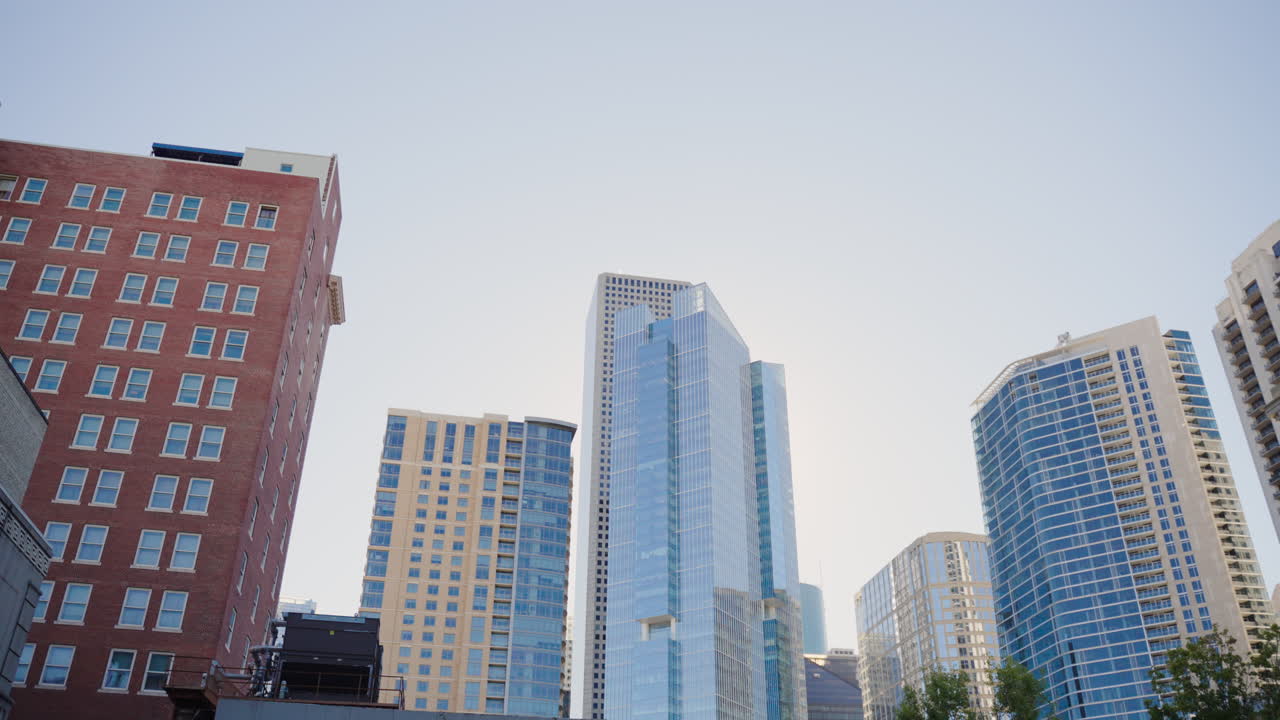 Vista panorâmica ao nível da rua do horizonte do centro de Houston, apresentando torres de escritórios modernas e arquitetura urbana, filmado com movimento de câmera da esquerda para a direita de um estacionamento durante o dia em Houston, Texas.