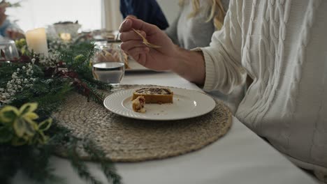 Close-up-of-plate-with-Christmas-cake-and-man-with-family-eating-them.