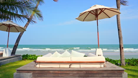 Camas-De-Playa-De-Lujo-Y-Sombrillas-Con-Impresionantes-Vistas-Al-Mar-Tropical-Y-Al-Horizonte-En-Un-Día-Soleado-De-Verano-Con-Brisa-Ligera,-Marco-Completo