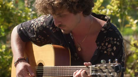 close-up of an italian man playing and feeling his acoustic guitar in a peaceful garden in anacapri, capri