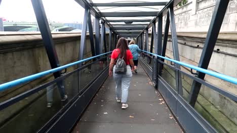 woman with glasses and red t-shirt going down a ramp to get a ferry through thames river