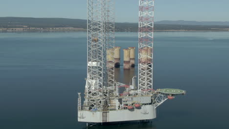 an aerial view of an oil rig on the cromarty firth on a sunny summer's day. rotating clockwise around the rig with zoom in.