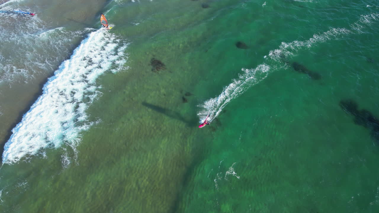 High angle drone shot following a wind surfer, surfing on the coast of Portugal