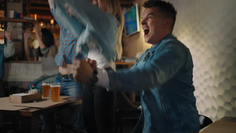 friends are watching together emotionally watching football on tv in a bar and celebrating the victory of their team after scoring a goal. the scored puck. fans in the pub