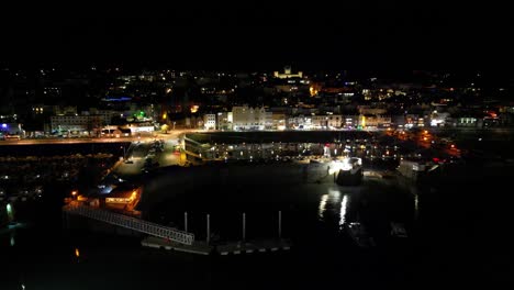 night flight into st peter port harbour guernsey featuring visitors marina and sea front with buildings lit in the background including elizabeth college