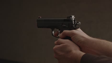 hand pulling back hammer of 9mm pistol and firing a bullet