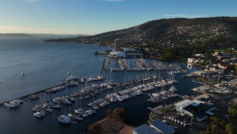 cruising boat arriving at the sailboat dock during sunset at hobart city, aerial