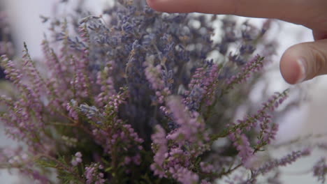 female hand puts a bouquet of lavender on a wooden table