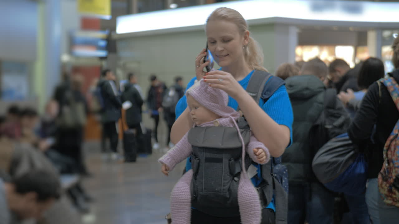 madre con la hija bebé esperando en el aeropuerto mujer hablando en el móvil