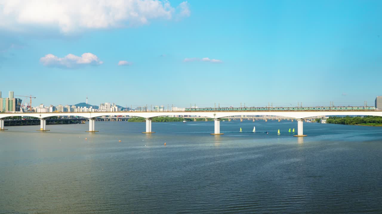 Two subway trains traveling in opposite directions meet in the middle of the Dangsan Railway Bridge over the Hangang River, with the iconic Namsan Tower and Seoul skyline in background